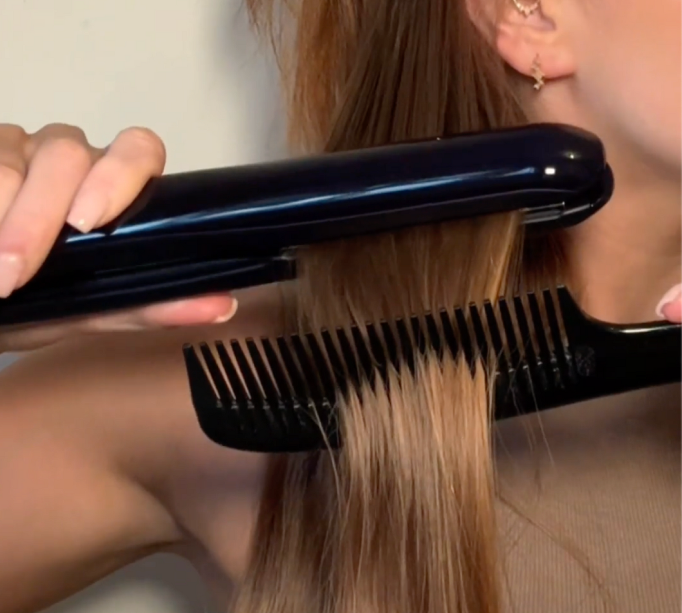 Close-up of a woman using the KEEO Smart Glide Straightener with a comb to smooth and straighten her hair, showcasing precision styling and sleek results.