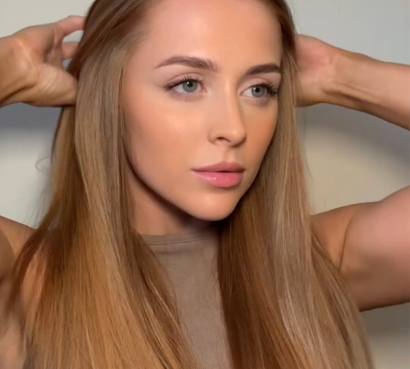 Woman with smooth, straight hair running her hands through it, showcasing the results of using the KEEO Smart Glide Straightener.