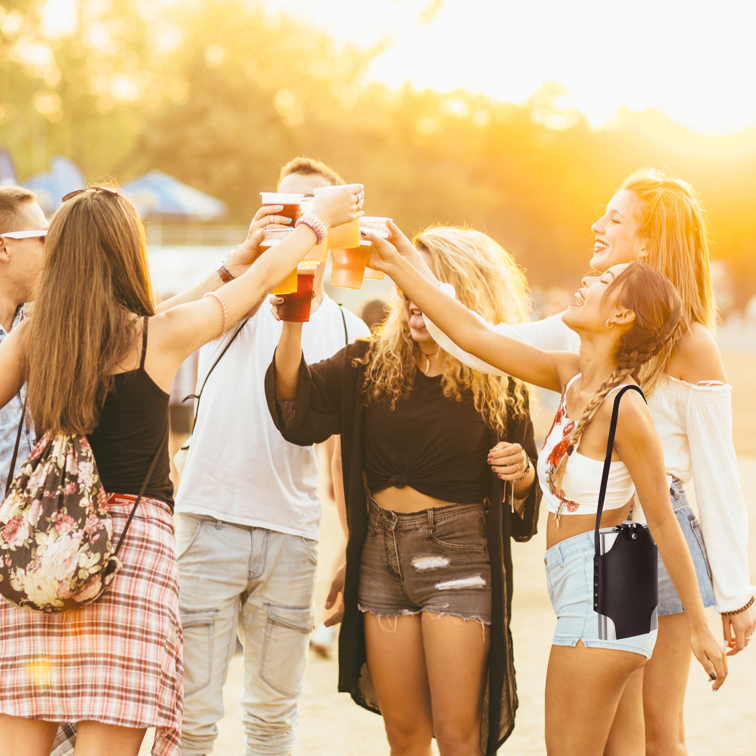 Group of friends at a music festival raising drinks together with a warm, golden light.