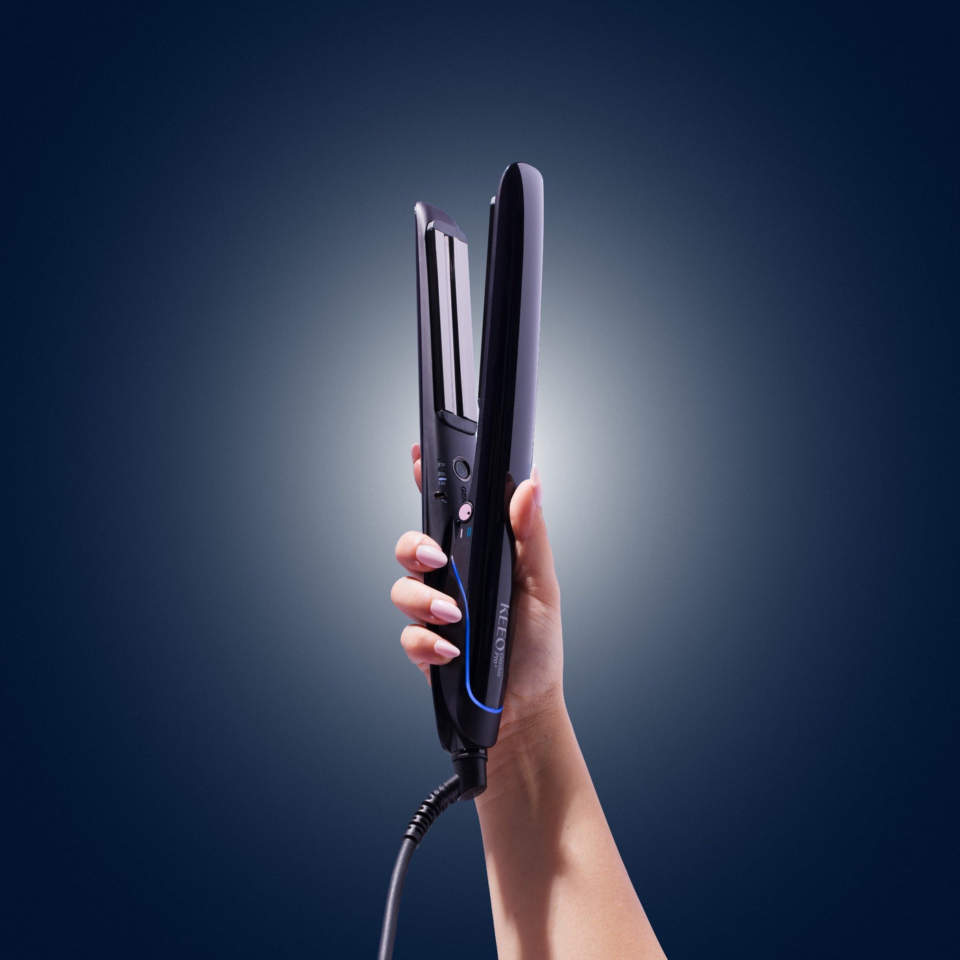 Hand holding a hair straightener against a dark background